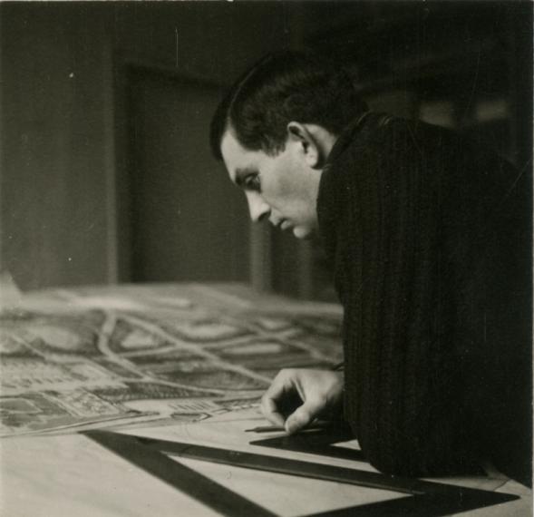 Documents biographiques : Pierre Dufau penché sur le plan de reconstruction d'Amiens, dans son agence d'Arcueil. 1941 (cliché anonyme).